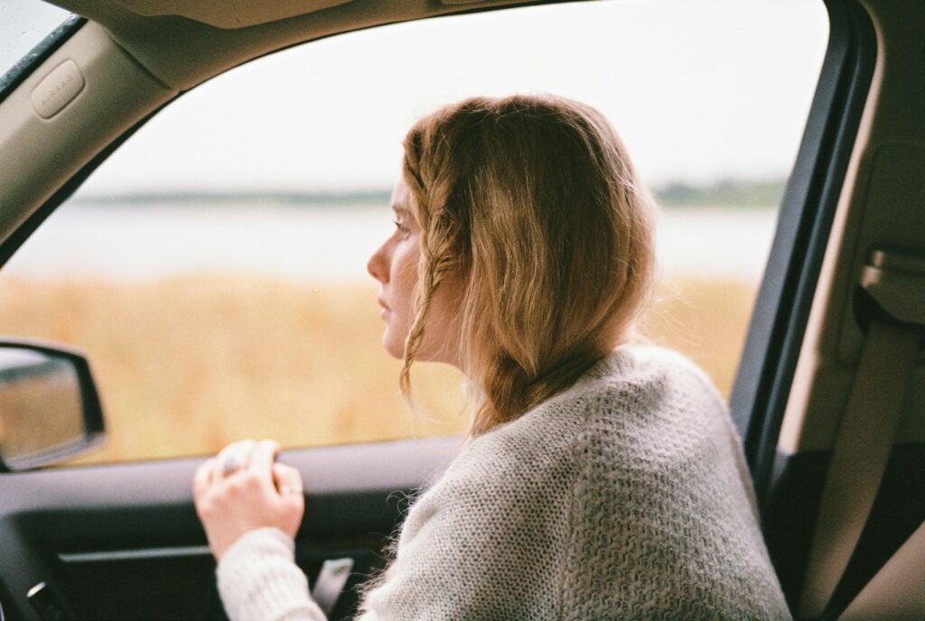 Woman sitting in car looking out the window, captured in a thoughtful moment during a road trip.
